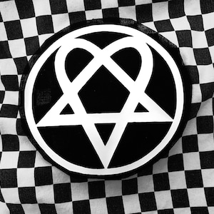 Könnte beinhalten: Ein schwarz-weißer Aufnäher mit einem weißen Pentagramm in einem Herzagramm-Design. Der Aufnäher ist kreisförmig und vor einem schwarzen Hintergrund platziert. Der Hintergrund ist ein schwarz-weißes Schachbrettmuster.
