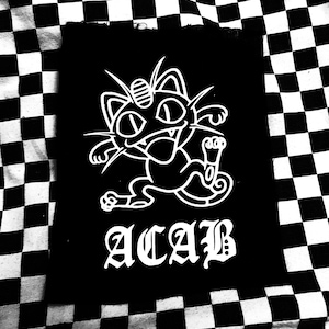 May include: Black and white iron-on patch with a cartoon image of a cat-like Pokemon character with the text "ACAB" in white.