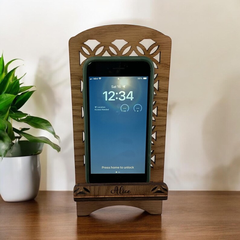 May include: A wooden phone stand with a decorative cutout design. The stand is personalized with the name "Alice".