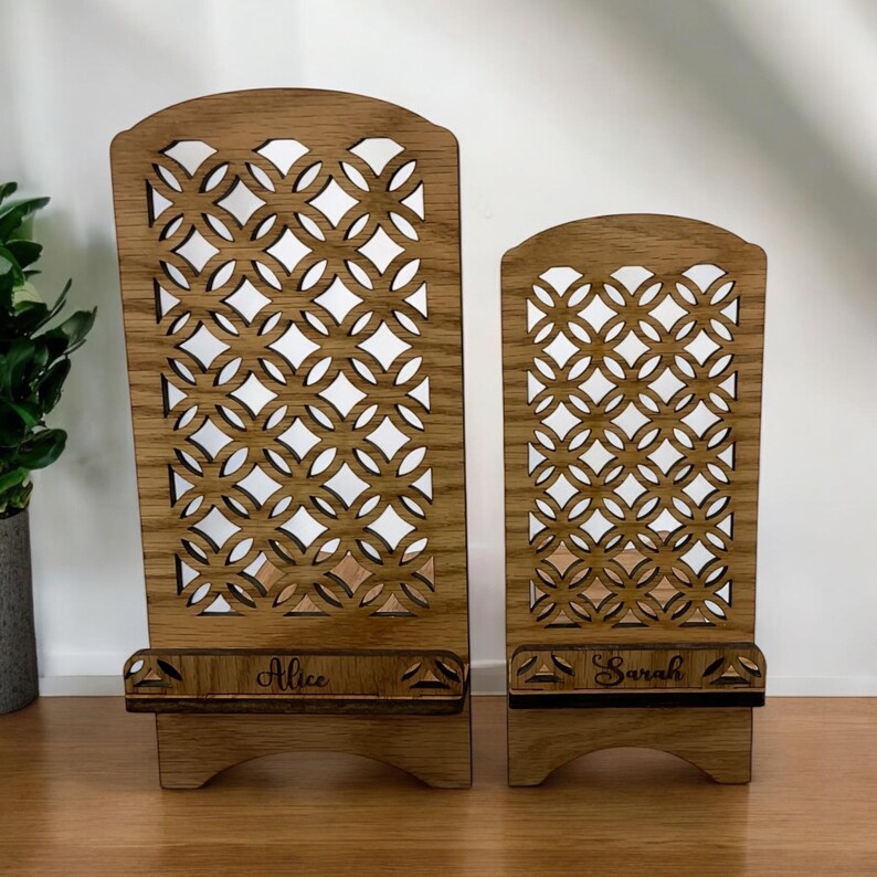 May include: Two wooden phone stands with a decorative lattice design. The larger stand is labeled "Alice" and the smaller stand is labeled "Sarah".
