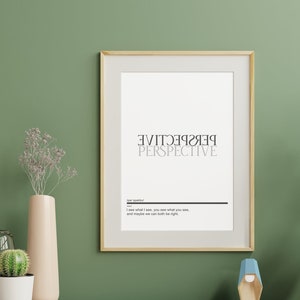 Op de afbeelding: Een ingelijst print met het woord "PERSPECTIVE" in zwart en wit. De tekst is gespiegeld en boven elkaar gestapeld. De print hangt aan een groene muur met een plant in een pot en een klein houten beeldje op een houten plank eronder.