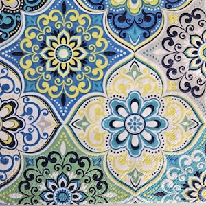May include: A blue, green, yellow, and white patterned fabric with a repeating geometric design. The fabric has a textured surface.