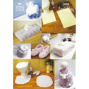 May include: A set of crocheted bathroom accessories in shades of pink and purple. The set includes a toilet seat cover, a tissue box cover, a bath mat, a pair of slippers, and a tissue box cover shaped like a doll. The pattern is called "Sprinkles" and the number is 3008.
