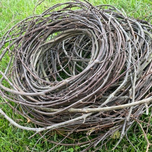 May include: A large bundle of brown grapevine wreath rings. The rings are stacked and twisted together, creating a natural and rustic look.