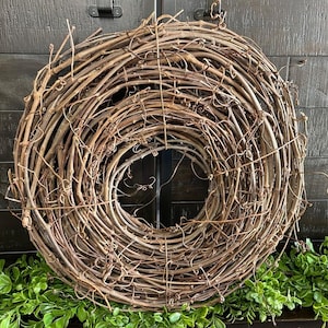 May include: A brown grapevine wreath, made of natural twigs, is a circular, rustic, and decorative item. It is perfect for adding a touch of nature to any space.
