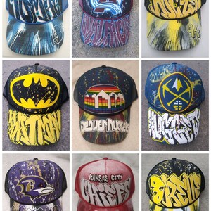 May include: Nine different baseball caps with various designs. The caps are all black mesh with a variety of colorful designs and logos. Some of the designs include a Batman logo, a Denver Nuggets logo, a Kansas City Chiefs logo, and a Ravens logo.