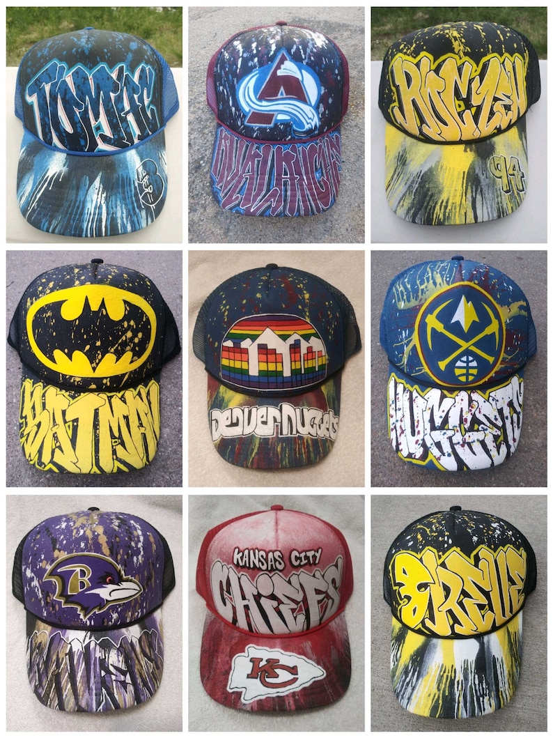 May include: Nine different baseball caps with various designs. The caps are all black mesh with a variety of colorful designs and logos. Some of the designs include a Batman logo, a Denver Nuggets logo, a Kansas City Chiefs logo, and a Ravens logo.