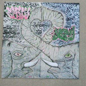 May include: Two gray elephant heads with pink and green accents, facing each other, with their trunks intertwined in a heart shape. The background is a white and gray abstract pattern with the words "Sorry" and "Smiley" written in pink and green.