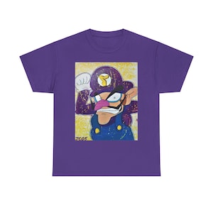 Könnte beinhalten: Lilafarbenes T-Shirt mit einem Aufdruck eines Comic-Charakters mit einem lila Hut, einem Schnurrbart und einer Latzhose. Der Charakter trägt einen goldenen Stern auf seinem Hut und hat einen gelben Hintergrund mit goldenem Glitzer. Der Text "JCOS" befindet sich in der linken unteren Ecke des Aufdrucks.