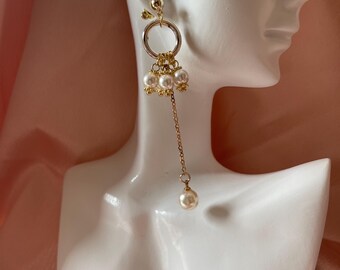 Peut inclure: Boucles d'oreilles pendantes dorées avec une goutte de perle et un charme circulaire avec plusieurs accents de perles.