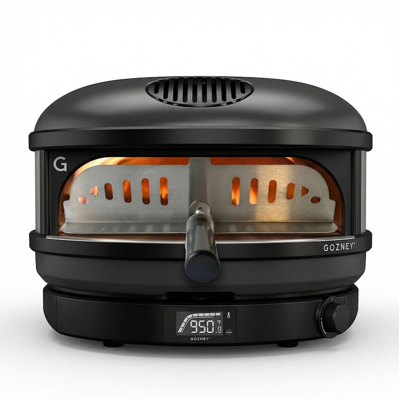 May include: Black outdoor pizza oven with the brand name "GOZNEY" visible. The oven features a digital temperature display showing 950 degrees Fahrenheit. The interior is lit with a warm glow, and a metal pizza peel is partially inserted.