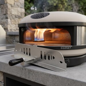 May include: A beige and black outdoor pizza oven with a stainless steel peel. The oven has a domed top and a rectangular opening displaying flames. The text "GOZNET" is printed on the front.