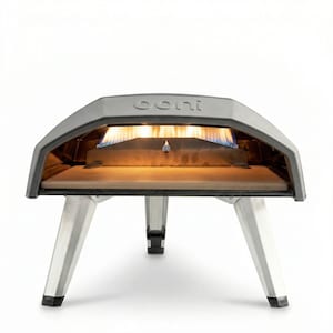 Peut inclure: Un four à pizza Ooni gris mat avec un extérieur en métal incurvé et trois pieds argentés robustes. L'intérieur présente une surface de cuisson en pierre plate et une rangée visible de flammes de gaz bleues et orange au fond du four.