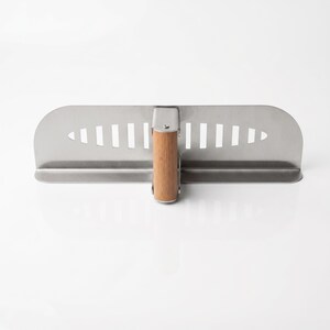 May include: A stainless steel plastering trowel with a wooden handle. The trowel has a rectangular blade with a series of vertical slots near the handle. The handle is made of light-colored wood and is attached to the blade with a metal bracket.