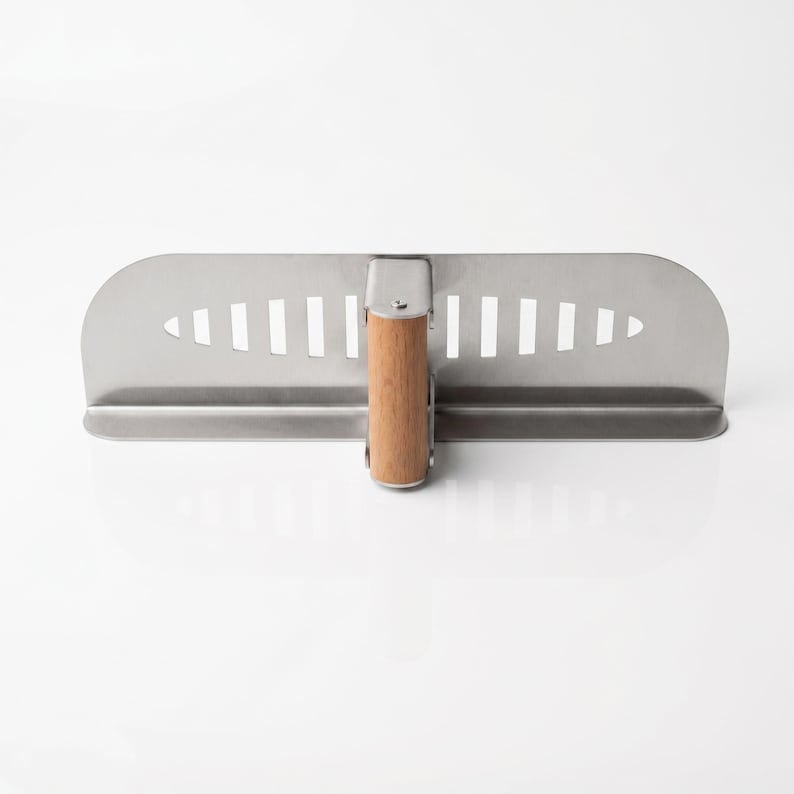 May include: A stainless steel plastering trowel with a wooden handle. The trowel has a rectangular blade with a series of vertical slots near the handle. The handle is made of light-colored wood and is attached to the blade with a metal bracket.