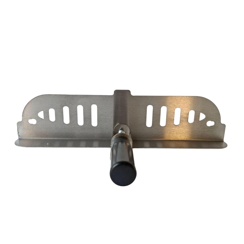 May include: A stainless steel grill scraper with a black handle. The scraper has a rectangular blade with several slots and a curved edge. The handle is cylindrical and made of black plastic.
