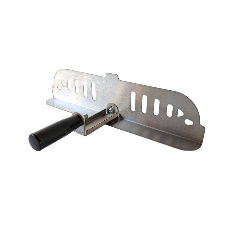 May include: A silver-colored metal tool with a black handle. The tool has a rectangular shape with several evenly spaced slots and a curved edge. A black handle is attached to the side with a bolt.