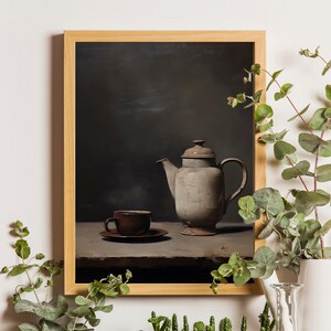Może przedstawiać: Martwa natura przedstawiająca brązowy ceramiczny czajnik i brązową ceramiczną filiżankę na drewnianym stole. Tło jest ciemnoszare.