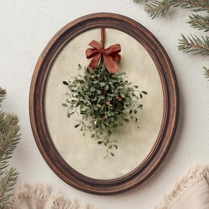 Può includere: Una cornice ovale in legno marrone scuro contenente la stampa di un rametto di vischio verde con piccole bacche rosse. Il vischio è legato con un nastro rosso scuro e pende su uno sfondo testurizzato color beige chiaro e bianco sporco.