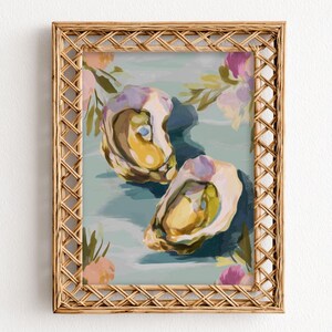 Könnte beinhalten: Ein gerahmter Kunstdruck mit zwei offenen Austern mit gelben und violetten Details, vor einem hellblauen Hintergrund mit floralen Akzenten. Der Rahmen besteht aus gewebtem, hellbraunem Material.