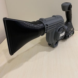May include: A gray and black power tool with a long nozzle attachment. The tool has a black handle and a gray body with the word "FLEX" printed on it.