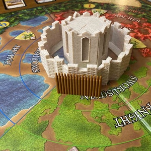 May include: A board game with a castle and wooden fence pieces. The castle is light beige with a circular design and arched windows. The game board features a map with text that reads "Knight", "Swords", and "Archer".
