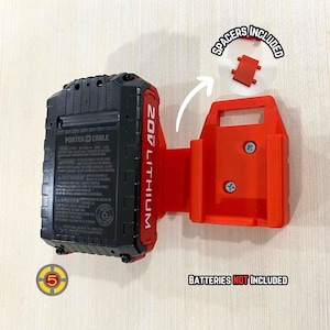 May include: Red plastic wall mount for a 20V lithium battery. The mount has two screw holes and a small slot for a battery. The text "SPACERS INCLUDED" is written on the mount. The text "BATTERIES NOT INCLUDED" is written below the mount. A black and gray 20V lithium battery is shown next to the mount.