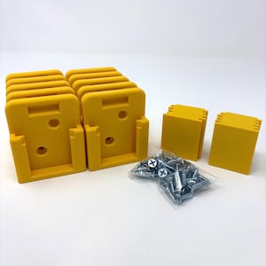 May include: A set of yellow plastic mounting brackets with rectangular bases and circular screw holes, accompanied by two stacks of yellow plastic rectangular spacers and a clear plastic bag containing multiple silver metal screws.
