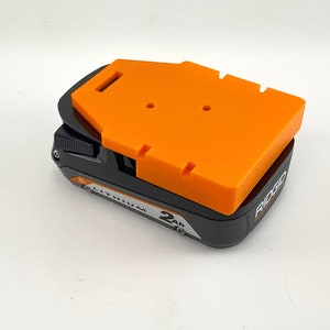 Puede incluir: Una bater&iacute;a de litio Ridgid de 18V 2Ah negra y naranja con una cubierta protectora naranja.
