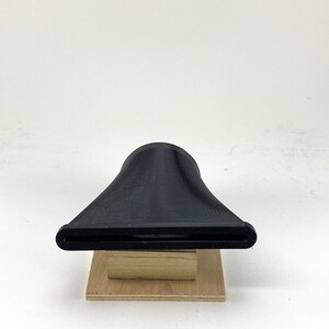 Puede incluir: Un embudo de pl&aacute;stico negro impreso en 3D con una abertura ancha y un pico estrecho, sentado sobre una base de madera.