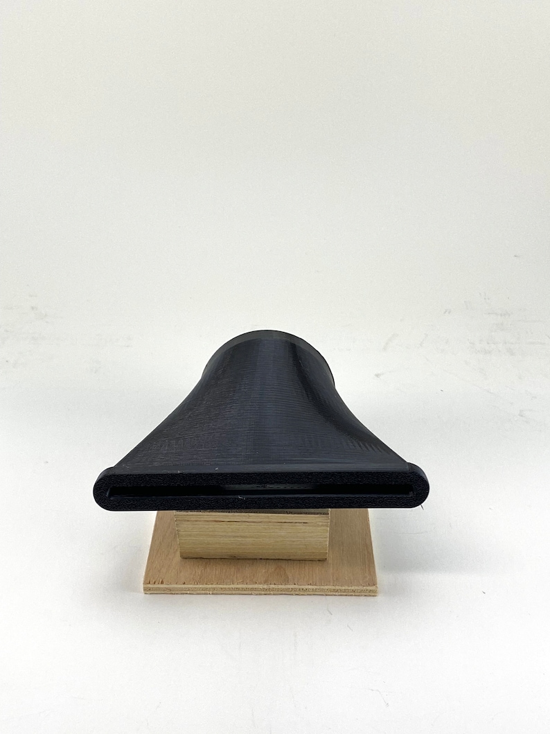 Puede incluir: Un embudo de pl&aacute;stico negro impreso en 3D con una abertura ancha y un pico estrecho, sentado sobre una base de madera.