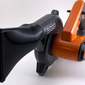 Puede incluir: Un soplador de hojas inal&aacute;mbrico negro y naranja con una boquilla larga. El soplador tiene la palabra "RIDGID" impresa en el lateral.