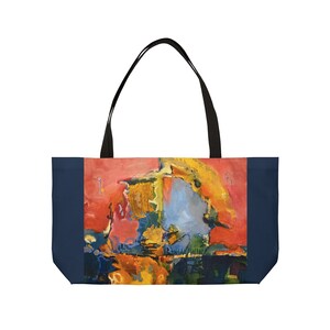 May include: A tote bag with a navy blue border and a colorful abstract painting of yellow, red, blue, and green. The painting appears to be of a landscape with a large, yellow, abstract shape in the center.