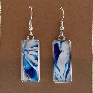 May include: A pair of silver dangle earrings with rectangular blue and white marbled resin inserts.