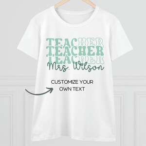 Może przedstawiać: Biała koszulka z zielonym nadrukiem, na kt&oacute;rym wielokrotnie widnieje napis "Teacher" oraz "Mrs. Wilson" na dole. Tekst "Customize your own text" jest r&oacute;wnież umieszczony wraz ze strzałką wskazującą na niego.