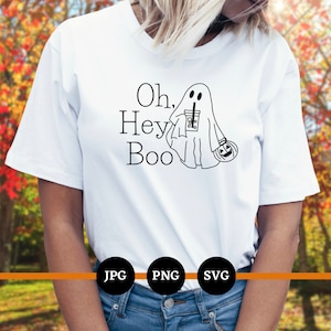 May include: A white t-shirt with a black and white illustration of a ghost holding a cup of coffee and a pumpkin. The text "Oh, Hey Boo" is printed on the shirt.