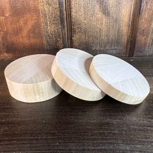 May include: Three wooden circles of varying sizes, stacked on top of each other. The circles are made of light-colored wood and have a smooth, polished finish.