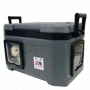 May include: A gray Igloo cooler modified as a pet shelter with two black-framed clear plastic doors on the sides. A white cat is visible through one door. A sticker on the front features a cat wearing American flag sunglasses with the text AMERICAN PET LOO.