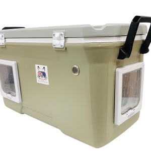 May include: A large, olive-green cooler with a light gray lid and black handle. It features two white-framed pet doors and a sticker with a cat and American flag design. The cooler has a vent and white latches. The cooler is designed for pet travel.