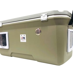 May include: A large, olive-green pet carrier with a gray lid and white accents. Features a small door on each side, a handle, and a sticker with a cat wearing sunglasses and the American flag. Includes a speaker.