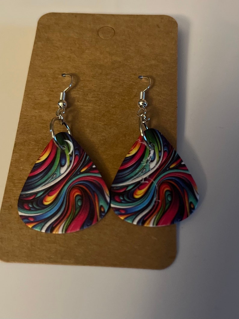 May include: A pair of teardrop-shaped earrings with a colorful abstract swirl pattern. The earrings are made of metal and have a silver hook closure.