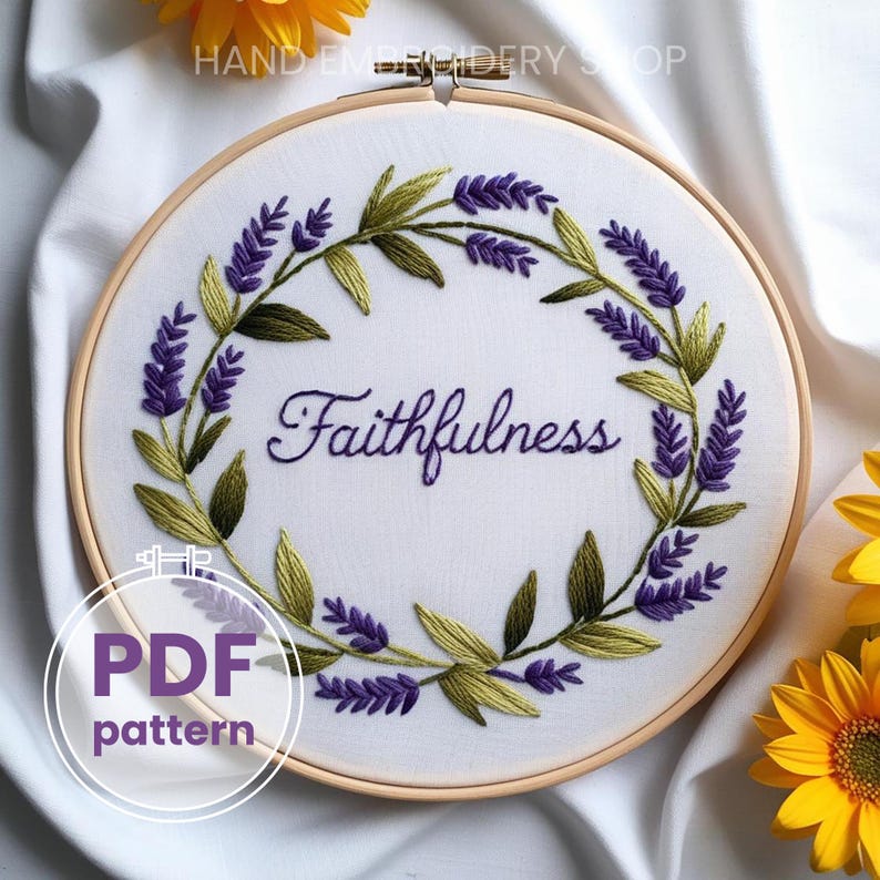 May include: A white embroidery hoop with a lavender wreath and the word "Faithfulness" embroidered in purple thread. The hoop is on a white fabric background.