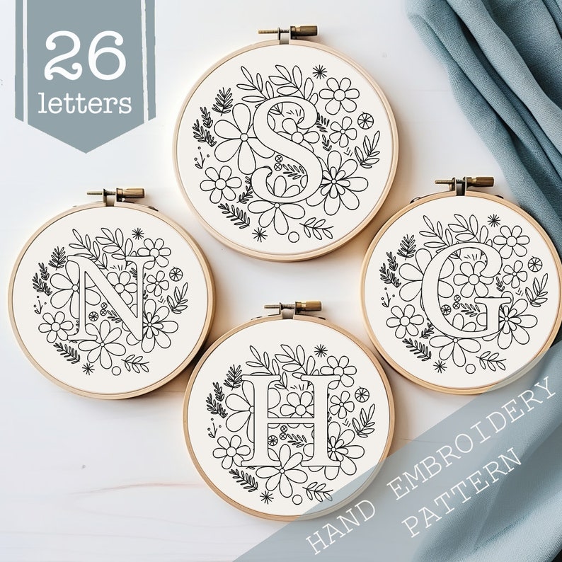 May include: Four embroidery hoop patterns featuring the letters N, S, H, and G surrounded by floral designs. The hoops are on a white surface with the text "HAND EMBROIDERY PATTERN" at the bottom right corner.