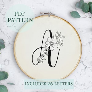 May include: A black and white embroidery pattern of the letter A with floral embellishments. The pattern includes 26 letters.