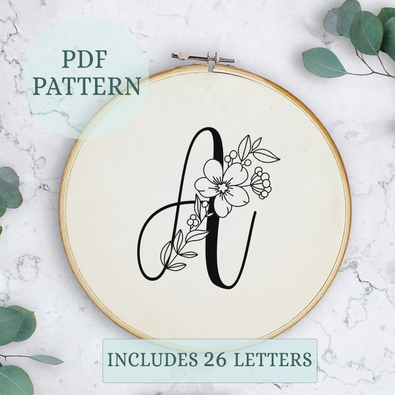 May include: A black and white embroidery pattern of the letter A with floral embellishments. The pattern includes 26 letters.