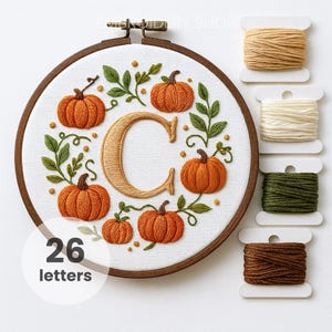 May include: Embroidered hoop art featuring orange pumpkins, green leaves, and the letter "C" in a fall theme. The text "26 letters" is in a white circle.  Spools of embroidery floss in various colors are to the right.
