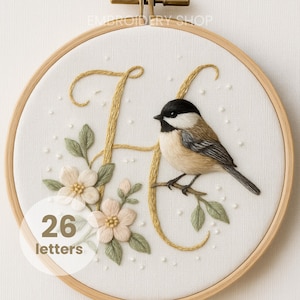 Puede incluir: Arte de aro bordado con un pájaro posado en una rama, con la letra "H" en hilo dorado. El diseño incluye delicadas flores y hojas en colores suaves, sobre un fondo de tela blanca. También se ve el texto "26 letters".