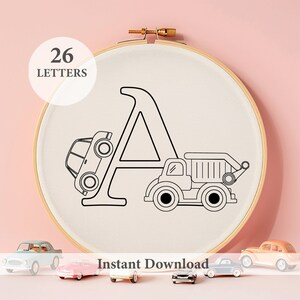May include: A black and white embroidery hoop with the letter A in the centre. A small car is behind the letter and a dumper truck is in front of the letter. The text "26 LETTERS" is in the top left corner of the image. The text "Instant Download" is at the bottom of the image.