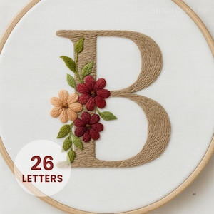 May include: Embroidered letter "B" in a wooden hoop. The letter is made of tan yarn and adorned with embroidered flowers in shades of red, peach, and green. The text "26 LETTERS" is in a white circle.