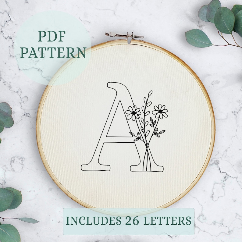 May include: A black and white embroidery pattern for the letter A with a floral design. The pattern includes 26 letters.